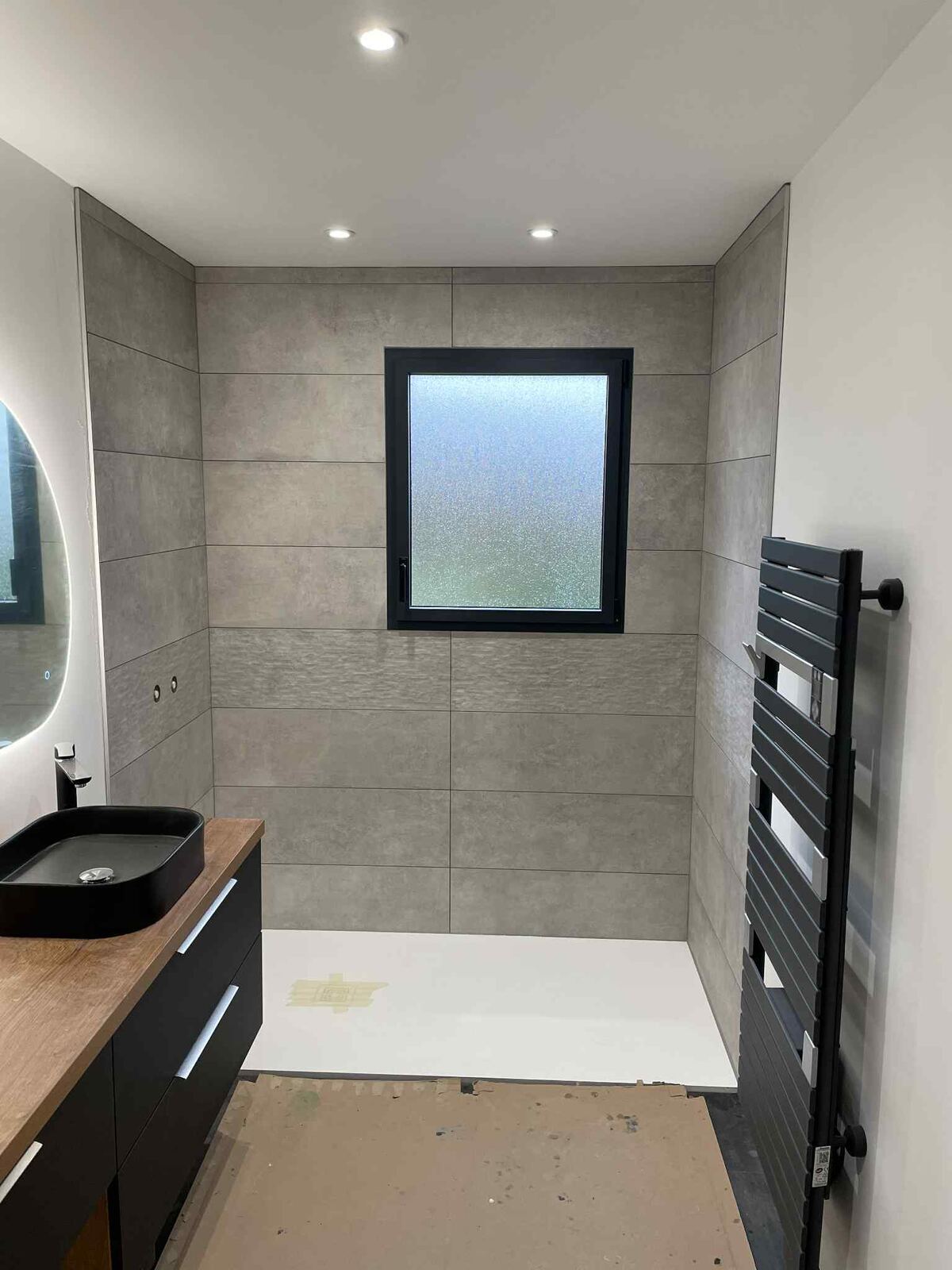 Salle de bain en cours de pose, receveur de douche et faïence grise