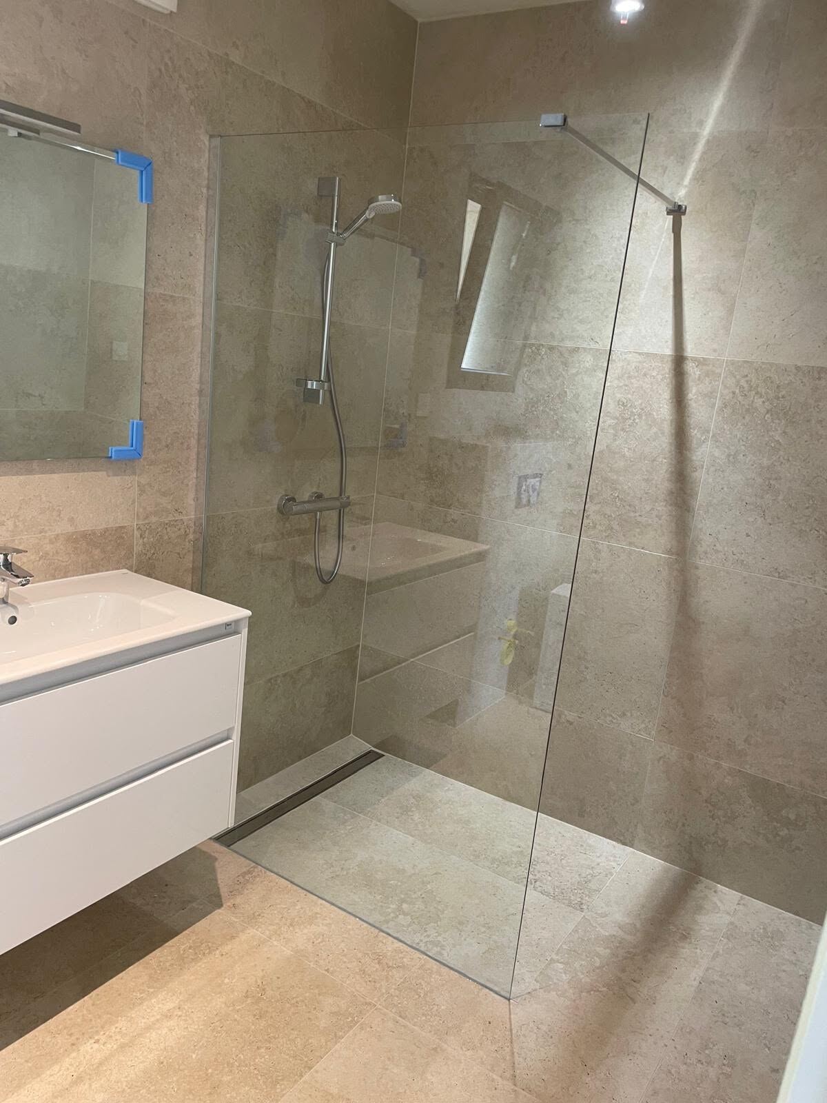 Salle de bain travertin avec paroi de douche en verre