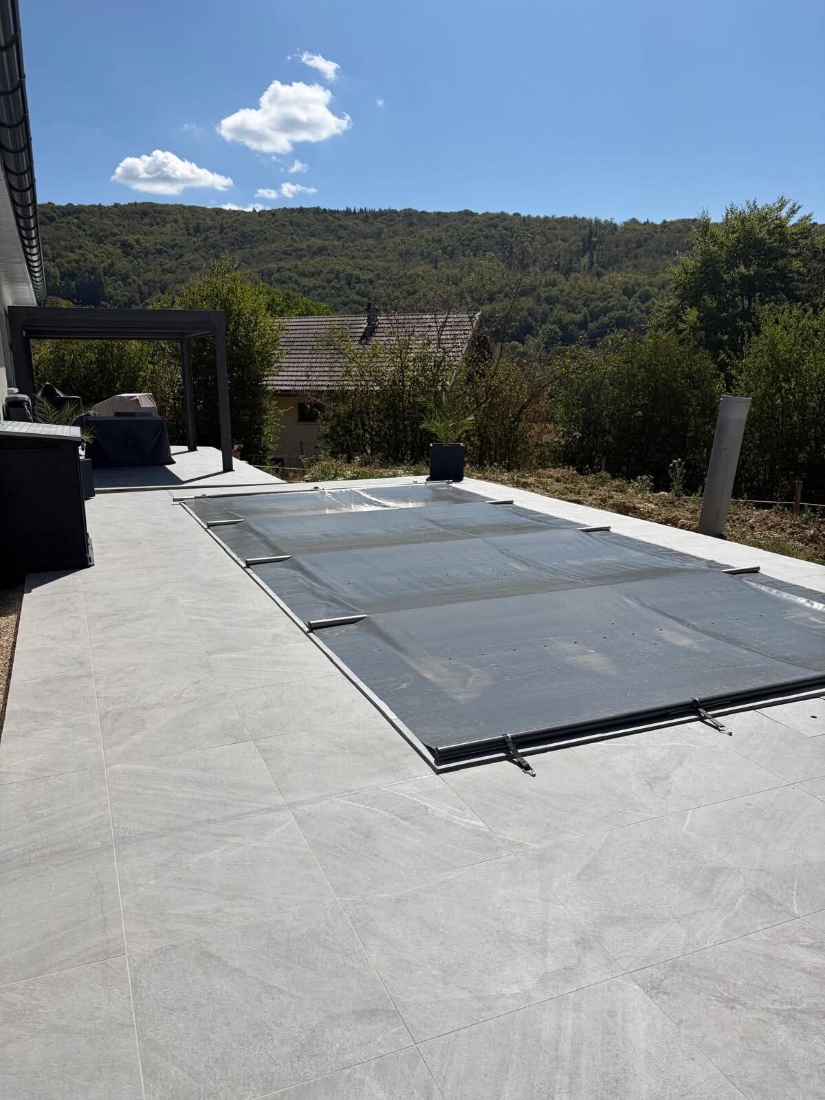 Terrasse en carrelage grand format gris avec bâche de piscine